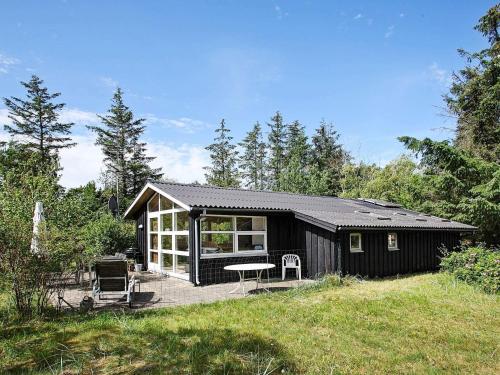 a black cabin with a patio and a table at 5 person holiday home in Jerup-By Traum in Jerup