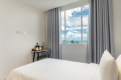 a white bedroom with a bed and a window at Nest by Hawks Hotels Kamadhoo Baa Atoll in Kamadhoo