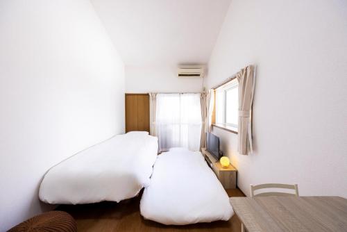 a small bedroom with two beds and a window at IL Regalo Tenjin Street Stay in Fukuoka