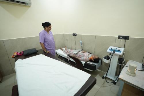 a woman standing next to a bed in a room at RIshikulam Wellness Centre in Samālkha