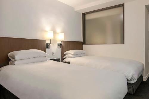 a hotel room with two beds and a mirror at United Hotel in Taipei