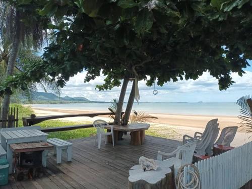 a wooden deck with chairs and a tree on the beach at Beach Front Villa, Saphli beach, Chumphon,Thailand in Ban Tha Samet (1)