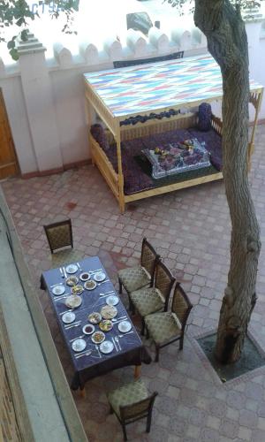 a table and chairs with plates on it next to a tree at Guest House Orzu in Khiva