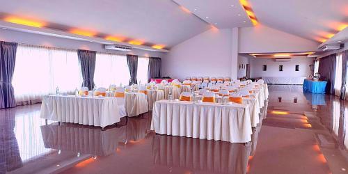 a room filled with tables and chairs with white table cloth at Gazebo Resort Pattaya in Pattaya Central