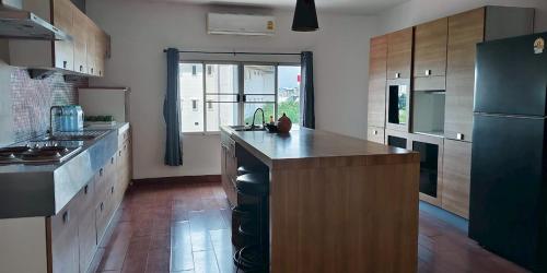 a kitchen with a black refrigerator and wooden cabinets at Gazebo Resort Pattaya in Pattaya Central