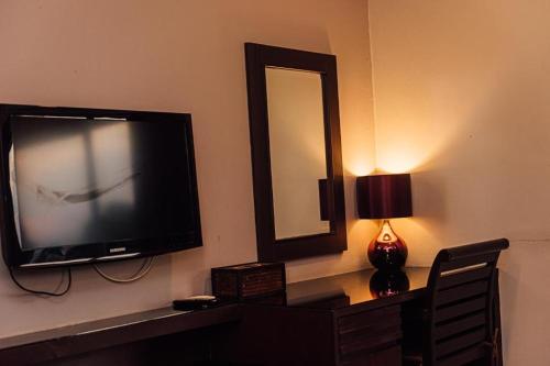 a television on a wall with a mirror and a lamp at Gazebo Resort Pattaya in Pattaya Central
