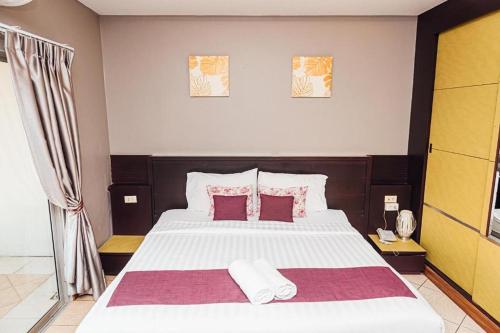 a bedroom with a large white bed with red pillows at Gazebo Resort Pattaya in Pattaya Central