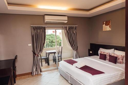 a bedroom with a bed and a table and a window at Gazebo Resort Pattaya in Pattaya Central