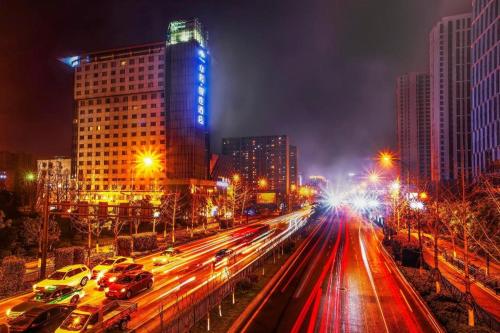 a busy city street at night with cars and buildings at Huachen Kenzo Hotel Hangzhou in Hangzhou