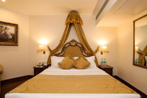 a bedroom with a large white bed with two pillows at Hotel The Royal Plaza in New Delhi