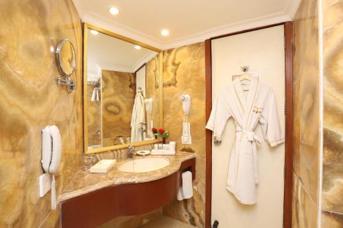 a bathroom with a sink and a white robe at Hotel The Royal Plaza in New Delhi