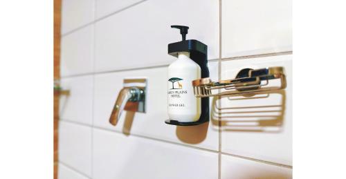 a bottle of hand soap is hanging on a bathroom wall at Karen Plains Hotel Nairobi in Nairobi