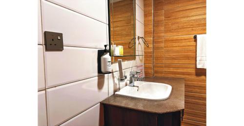 a bathroom with a sink and wooden walls at Karen Plains Hotel Nairobi in Nairobi