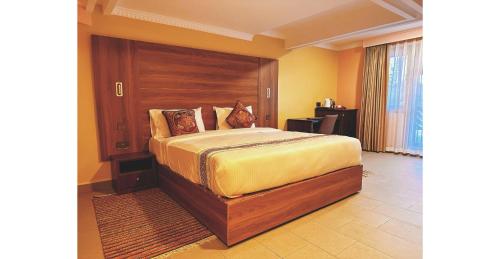 a bedroom with a bed with a wooden headboard at Karen Plains Hotel Nairobi in Nairobi