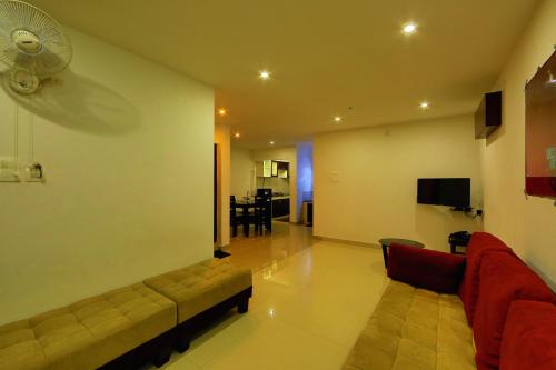 a living room with a couch and a fan at Sara Hotels and Apartments in Nedumbassery