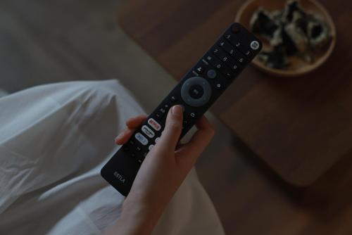 a person holding a remote control in their hand at Aank Ryokan Hotel Ansan Seonbu Branch in Ansan