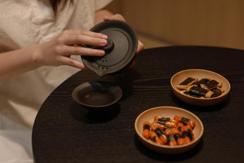 a woman taking a picture of a table with bowls of food at Aank Ryokan Hotel Ansan Seonbu Branch in Ansan