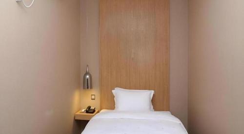 a bedroom with a white bed and a wooden headboard at The Art Hotel in Shenzhen