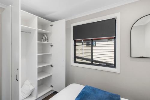 a white bedroom with a window and a bed at Moss Vale Village Park in Moss Vale