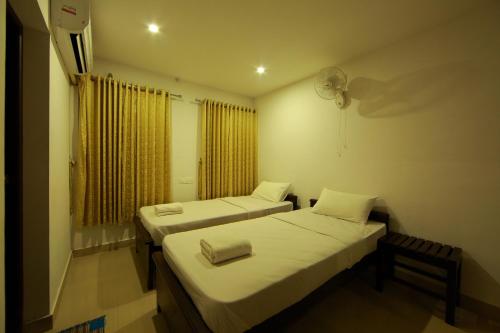 two beds in a small room with a window at Sara Hotels and Apartments in Nedumbassery