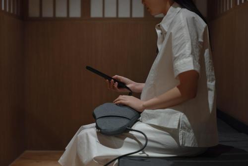 a woman in a white dress sitting on a chair with a hair dryer at Aank Ryokan Hotel Ansan Seonbu Branch in Ansan
