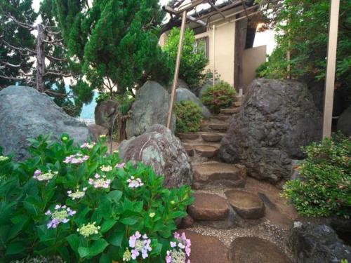 a garden with rocks and flowers in front of a house at Meitei no Yado Hotel Koshien in Fuefuki
