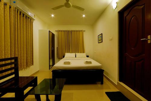 a bedroom with a bed and a table and a window at Sara Hotels and Apartments in Nedumbassery