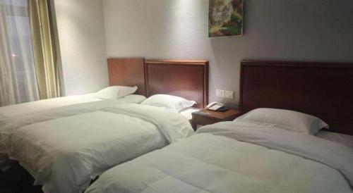 a hotel room with three beds with white sheets at GreenTree Inn Yancheng Vehicle Administrative office Test Center Express Hotel in Yancheng