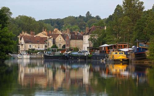 a group of boats docked in a river near a town at Maison Simone in Samois-sur-Seine