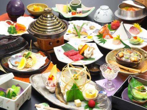 a table with many plates of food on it at Meitei no Yado Hotel Koshien in Fuefuki