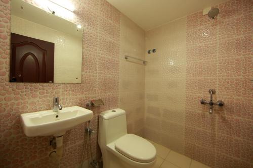 a bathroom with a sink and a toilet and a mirror at Sara Hotels and Apartments in Nedumbassery