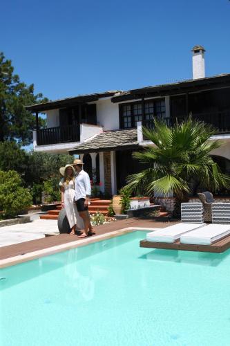 a man and a woman standing next to a swimming pool at Byblos Luxury Villa in Prinos