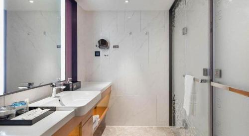 a bathroom with a sink and a shower with a mirror at Hampton by Hilton Zhuhai Doumen in Zhuhai
