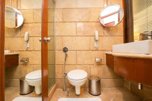 a bathroom with two toilets and a sink and mirrors at Hotel The Royal Plaza in New Delhi