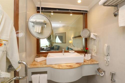 a bathroom with a sink and a mirror at Hotel The Royal Plaza in New Delhi