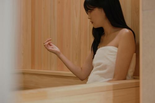 a woman in a white dress sitting in a bathtub at Aank Ryokan Hotel Ansan Seonbu Branch in Ansan
