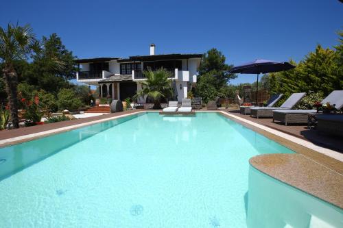 a large blue swimming pool with chairs and an umbrella at Byblos Luxury Villa in Prinos