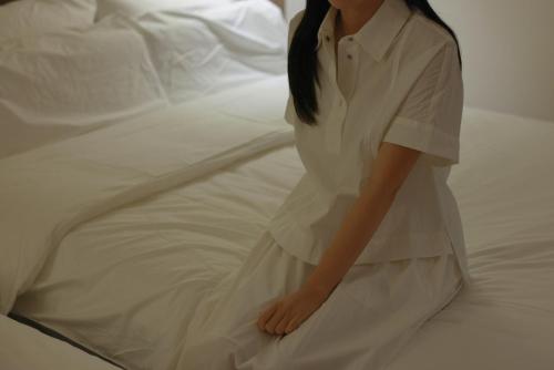 a woman in a white dress sitting on a bed at Aank Ryokan Hotel Ansan Seonbu Branch in Ansan