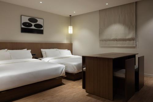 a hotel room with two beds and a desk at Aank Ryokan Hotel Ansan Seonbu Branch in Ansan