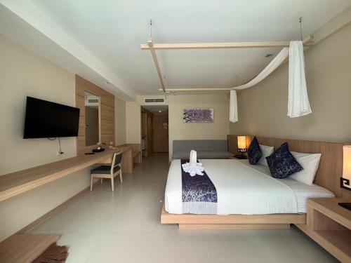 a bedroom with a bed and a desk and a television at Apasari Krabi - SHA Extra Plus in Ao Nang Beach