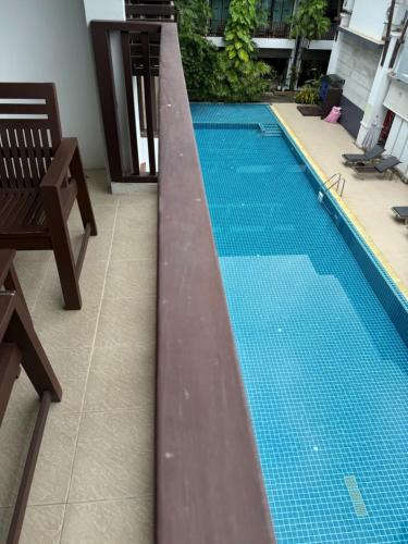 a swimming pool with a wooden railing next to a chair at Apasari Krabi - SHA Extra Plus in Ao Nang Beach