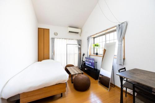 ein Schlafzimmer mit einem Bett, einem Schreibtisch und einem Tisch in der Unterkunft IL Regalo Tenjin2 Street Stay in Fukuoka