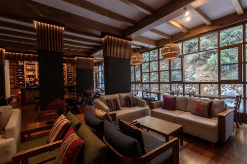 a living room with couches and tables and windows at Casa del Sol Machupicchu in Machu Picchu