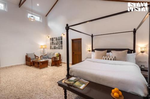 une chambre avec un grand lit et une chaise dans l'établissement StayVista at The Floramer with Bonfire, Lawn, à Panchgani