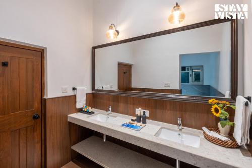 une salle de bain avec deux lavabos et un grand miroir dans l'établissement StayVista at The Floramer with Bonfire, Lawn, à Panchgani