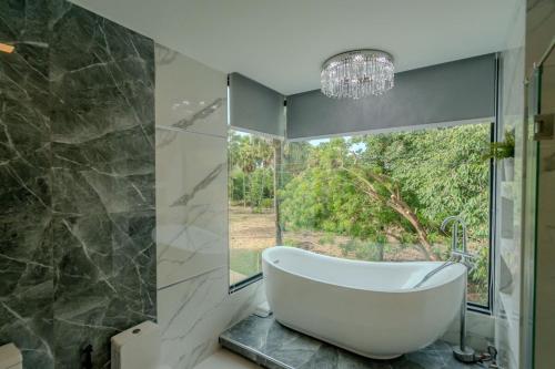 a bath tub in a bathroom with a large window at Villa Aftersol Cha-Am in Cha Am