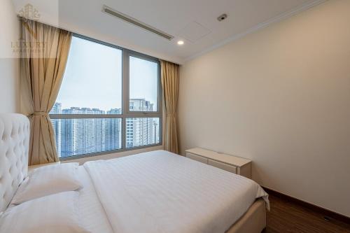 a bedroom with a white bed and a large window at The Peak Suite at Landmark Plus in Ho Chi Minh City