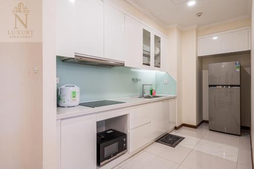 a kitchen with white cabinets and a sink and a microwave at The Peak Suite at Landmark Plus in Ho Chi Minh City
