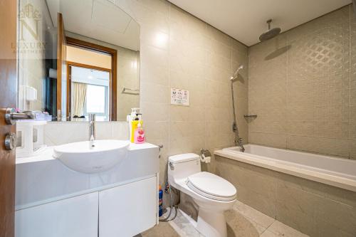 a bathroom with a sink and a toilet and a tub at The Peak Suite at Landmark Plus in Ho Chi Minh City