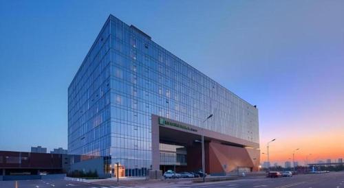 a large glass office building with a parking lot at Holiday Inn Express Handan East By IHG in Handan